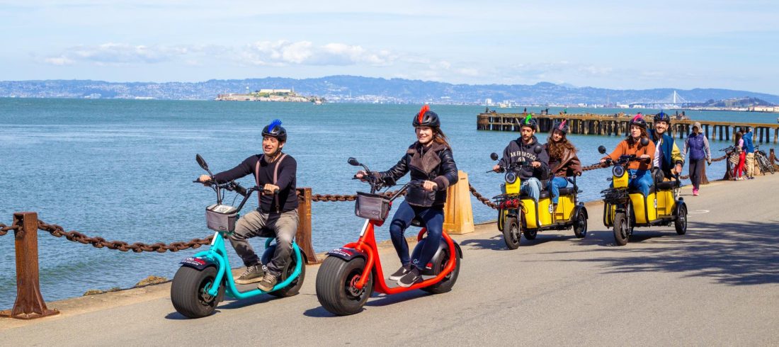 Electric Scooter Rentals ride past the iconic Fishermans Wharf Sign - Rent an E-scooter with fully guided GPS GoRide tour to the Golden Gate Bridge - departs from Umbrella Alley